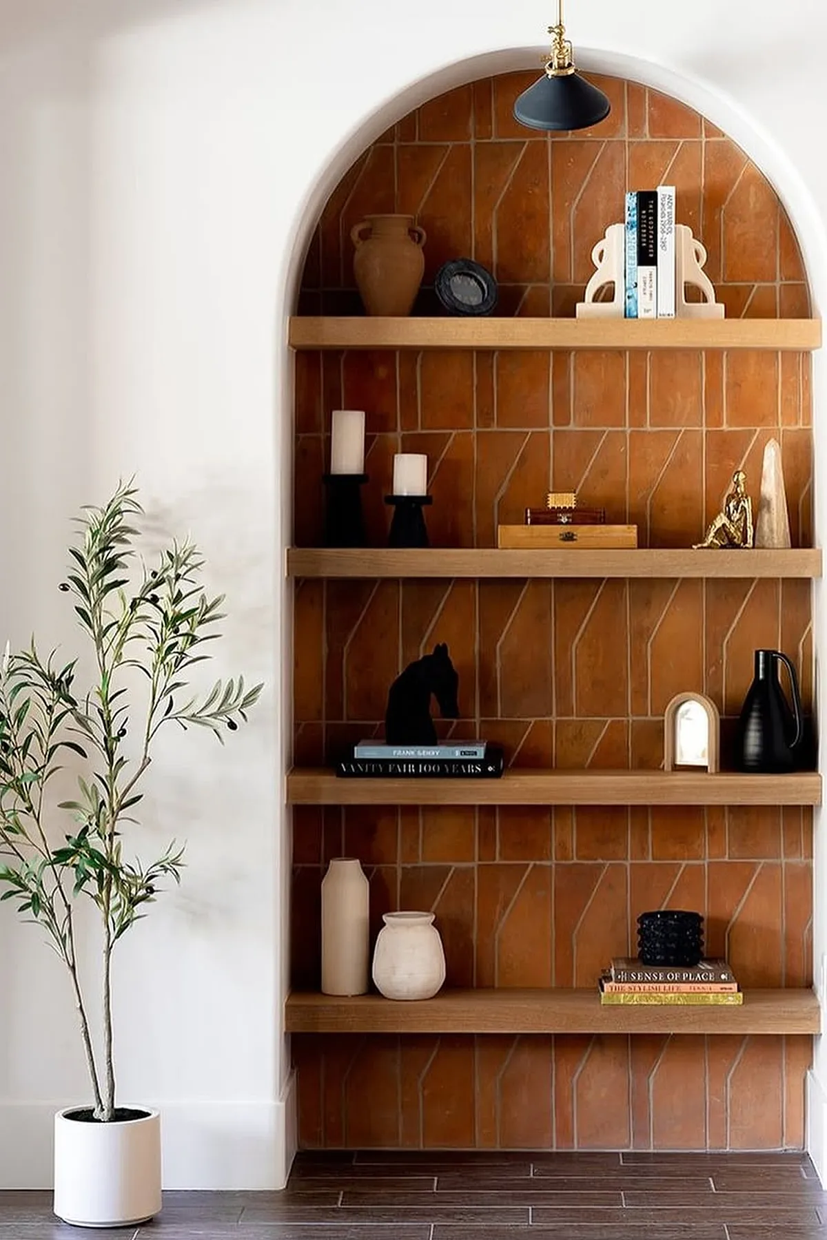 Stylish shelf featuring wooden shelves, terracotta tile background, candles, vases, and decorative objects.